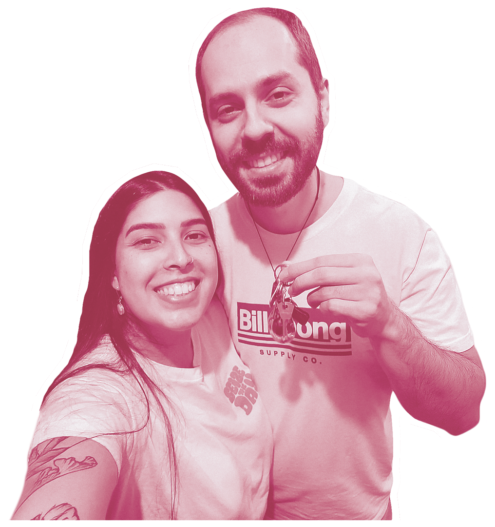 Michelle (esquerda) e Martin (Red - direita) sorrindo abraçados enquanto Martin mostra a chave da sua nova casa em mãos.